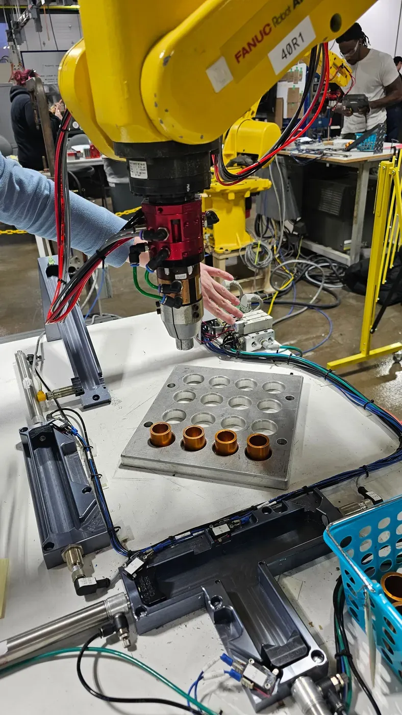 A yellow industrial robot arm being worked on in a robotics classroom