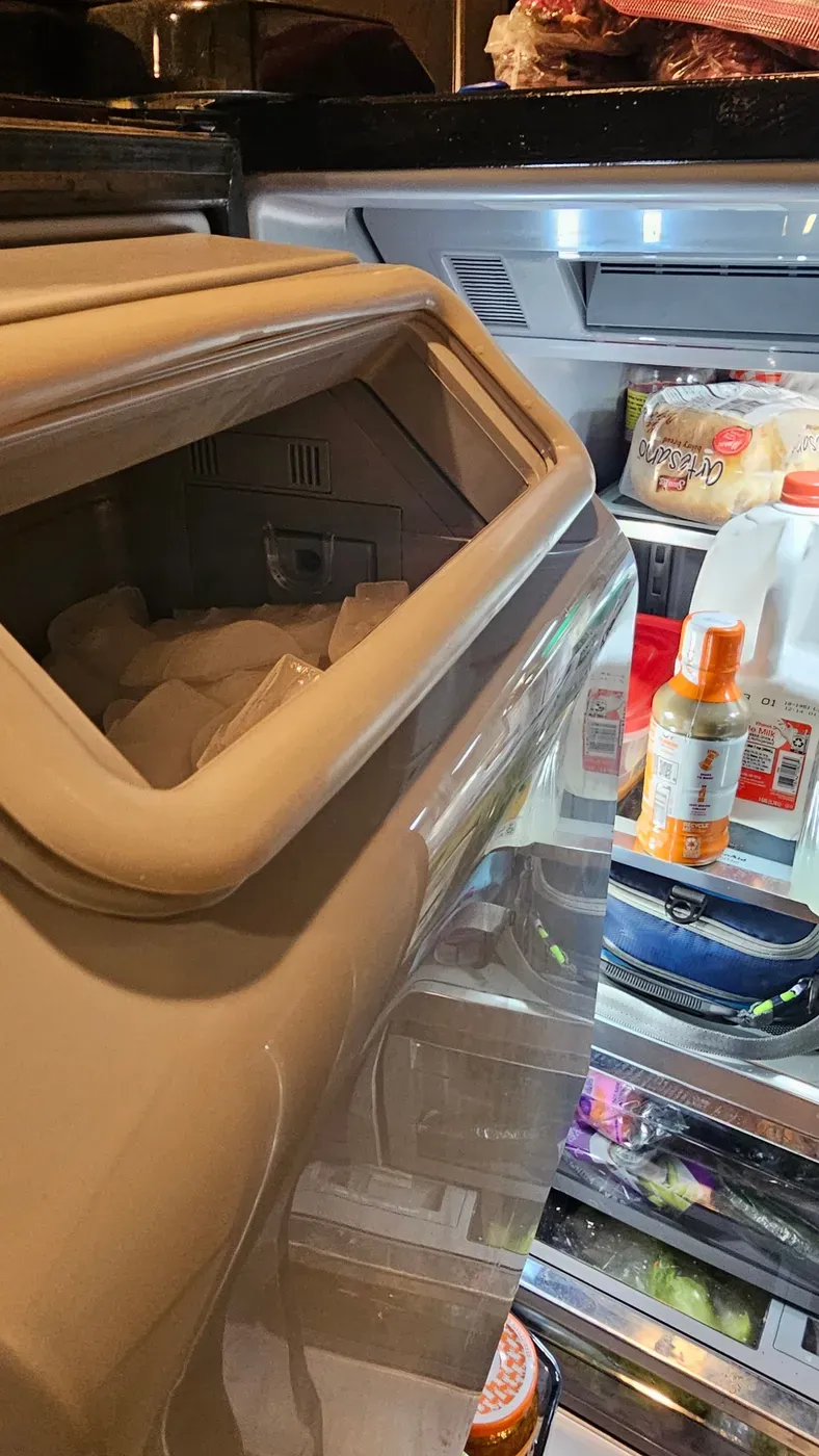 A phone wedged inside the ice bucket of a French-door refrigerator, having slid off the top